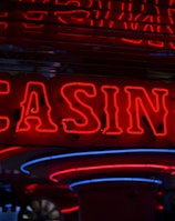 Neon lights display the word 'CASINO' in bright red, standing out against a dark background. The vibrant glow reflects a lively and bustling atmosphere.
