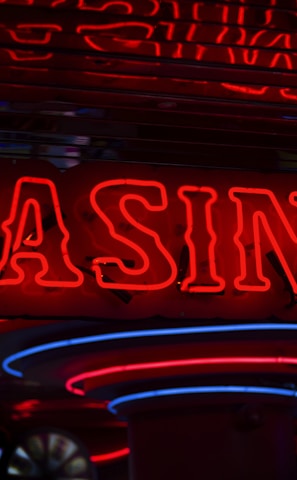 Neon lights display the word 'CASINO' in bright red, standing out against a dark background. The vibrant glow reflects a lively and bustling atmosphere.